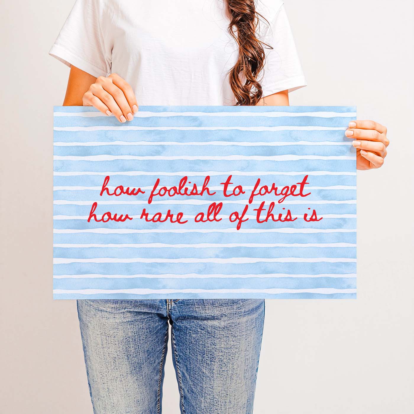Person holding a sign with motivational quote on a plain background